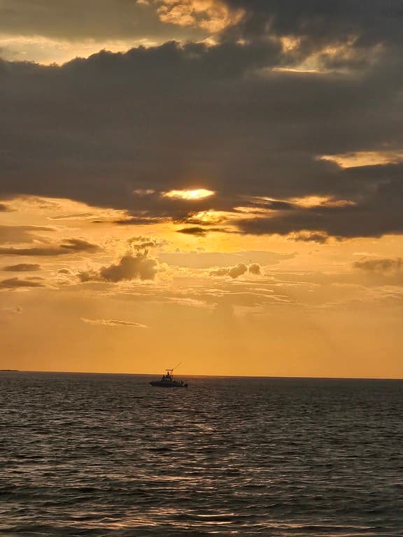Sunset silhouettes fishing boat on the open ocean