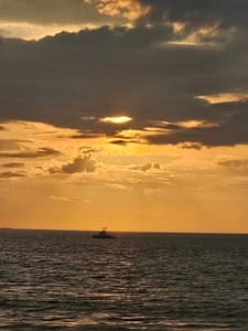 Sunset silhouettes fishing boat on the open ocean